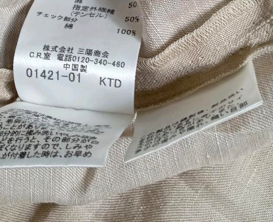 品質表示タグの表示者名。株式会社三陽商会と電話番号が印字されている