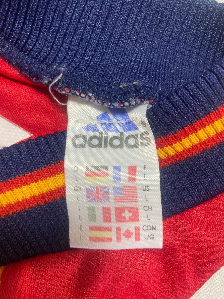 3本のバーのロゴと adidas の文字、8か国の国旗とサイズLが並ぶタグ