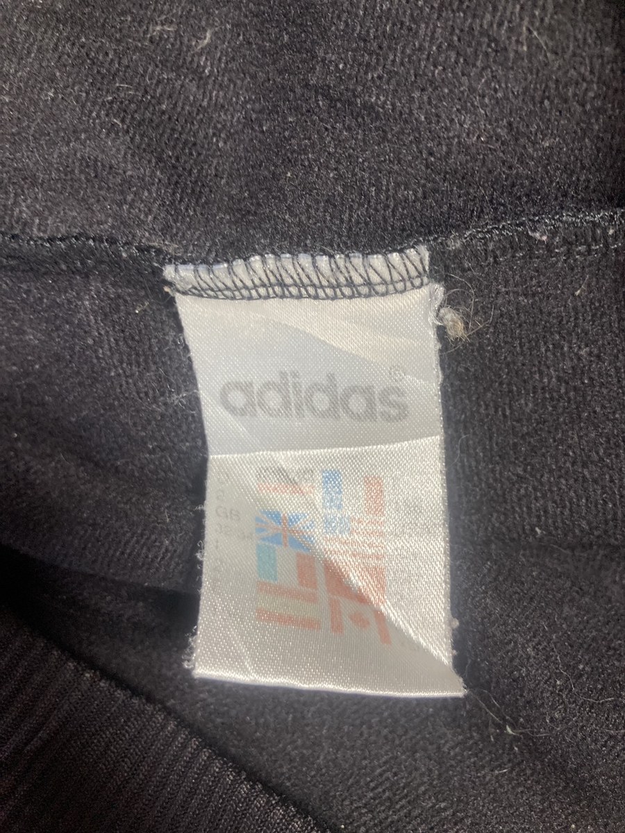 adidas の文字と、国旗とサイズが並ぶ白いタグ