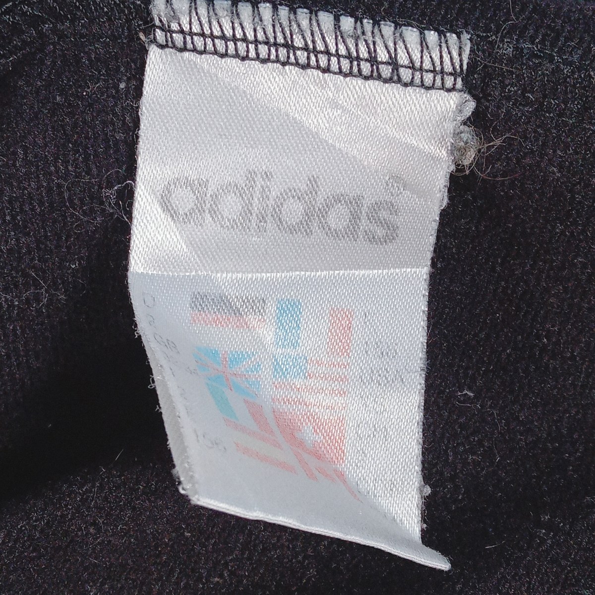 アディダスの白いタグ。adidasの文字と国旗が並ぶ